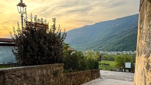 Un chemin pavé mène à un bâtiment où se trouvent un lampadaire et un panneau indicateur.