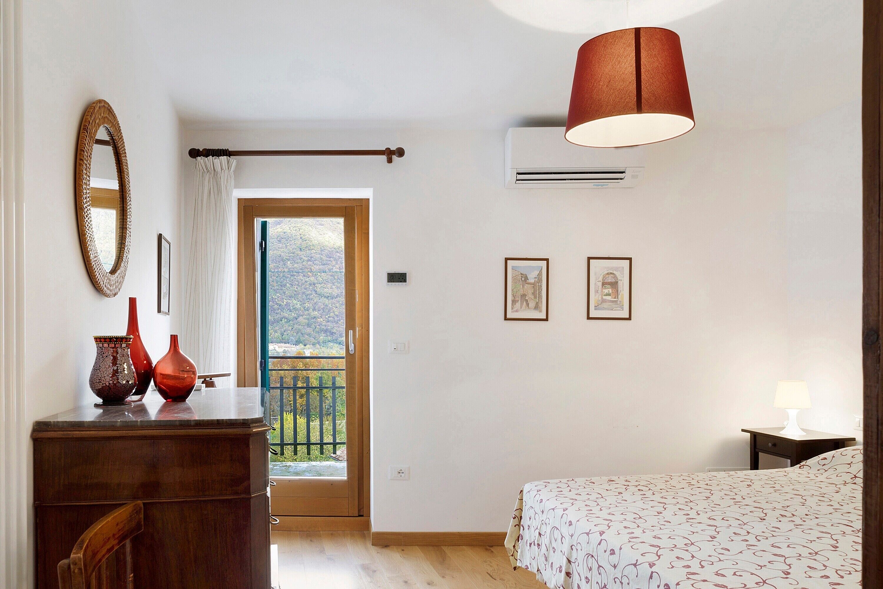 A bedroom with a bed, dresser, mirror, and two framed pictures.