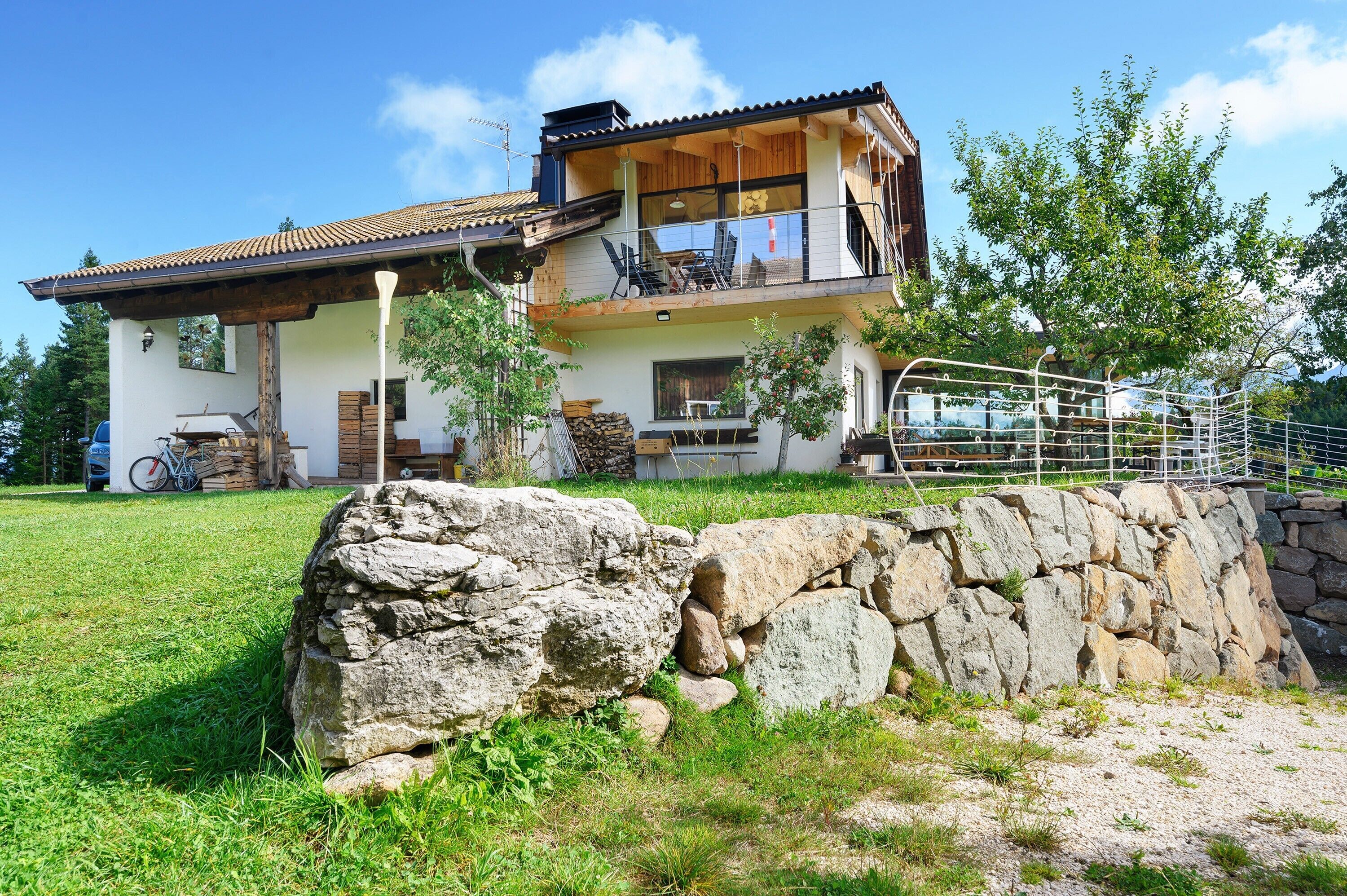 A two-story house with a balcony, a stone wall, and a bicycle.