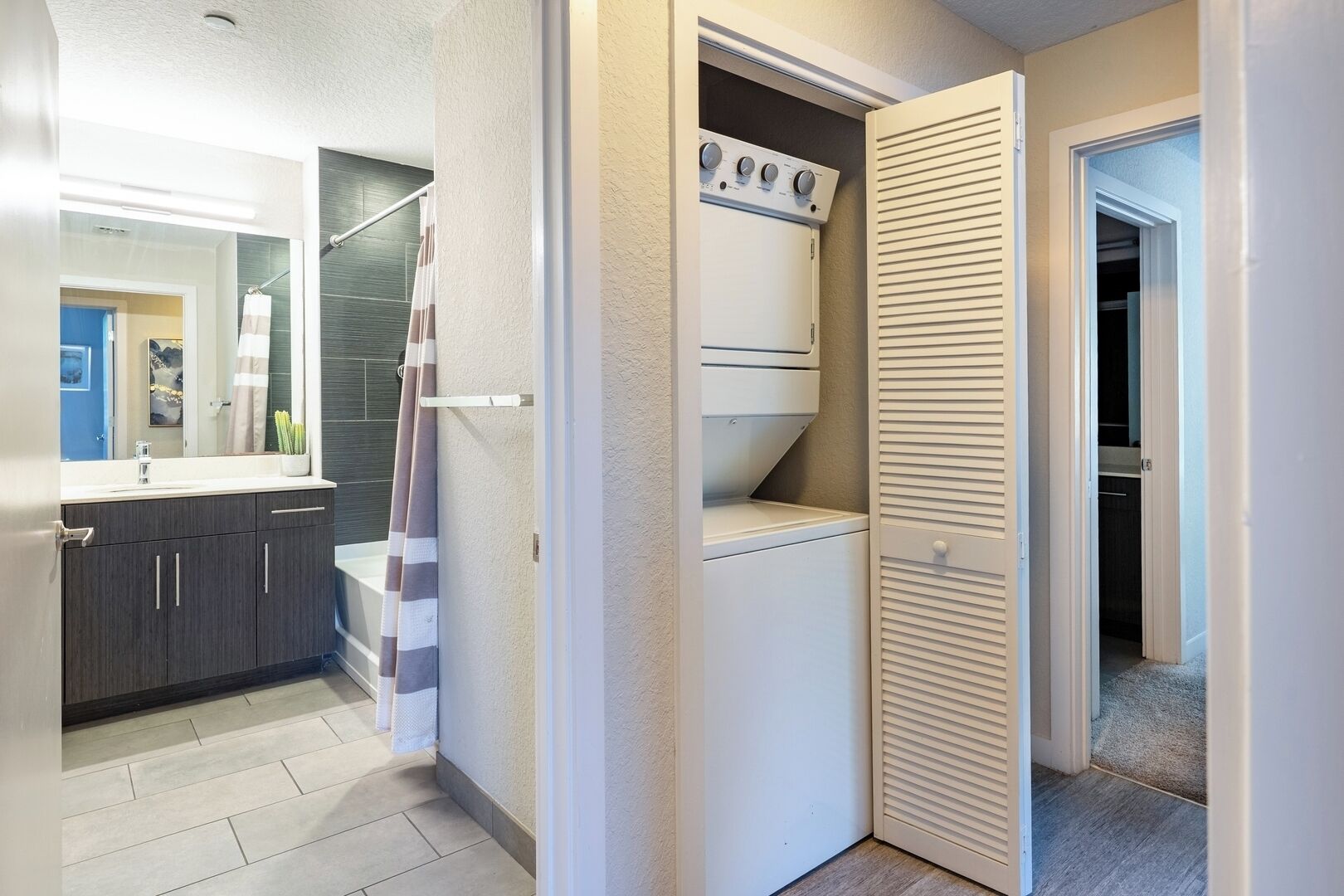 A compact laundry room with a washing machine, dryer, and a closed closet.
