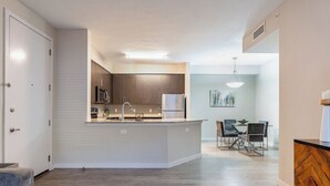 Una cucina moderna con isola centrale, mobili in legno e zona pranzo con tavolo e sedie.