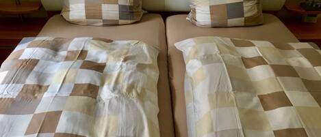 A double bed with a checkered bedspread and two pillows with a similar pattern.