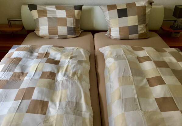Ein Doppelbett mit einer karierten Tagesdecke und zwei Kissen in ähnlichem Muster.
