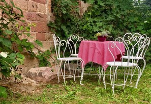 Un jardin agrémenté d’une table à carreaux et de chaises en métal blanc.