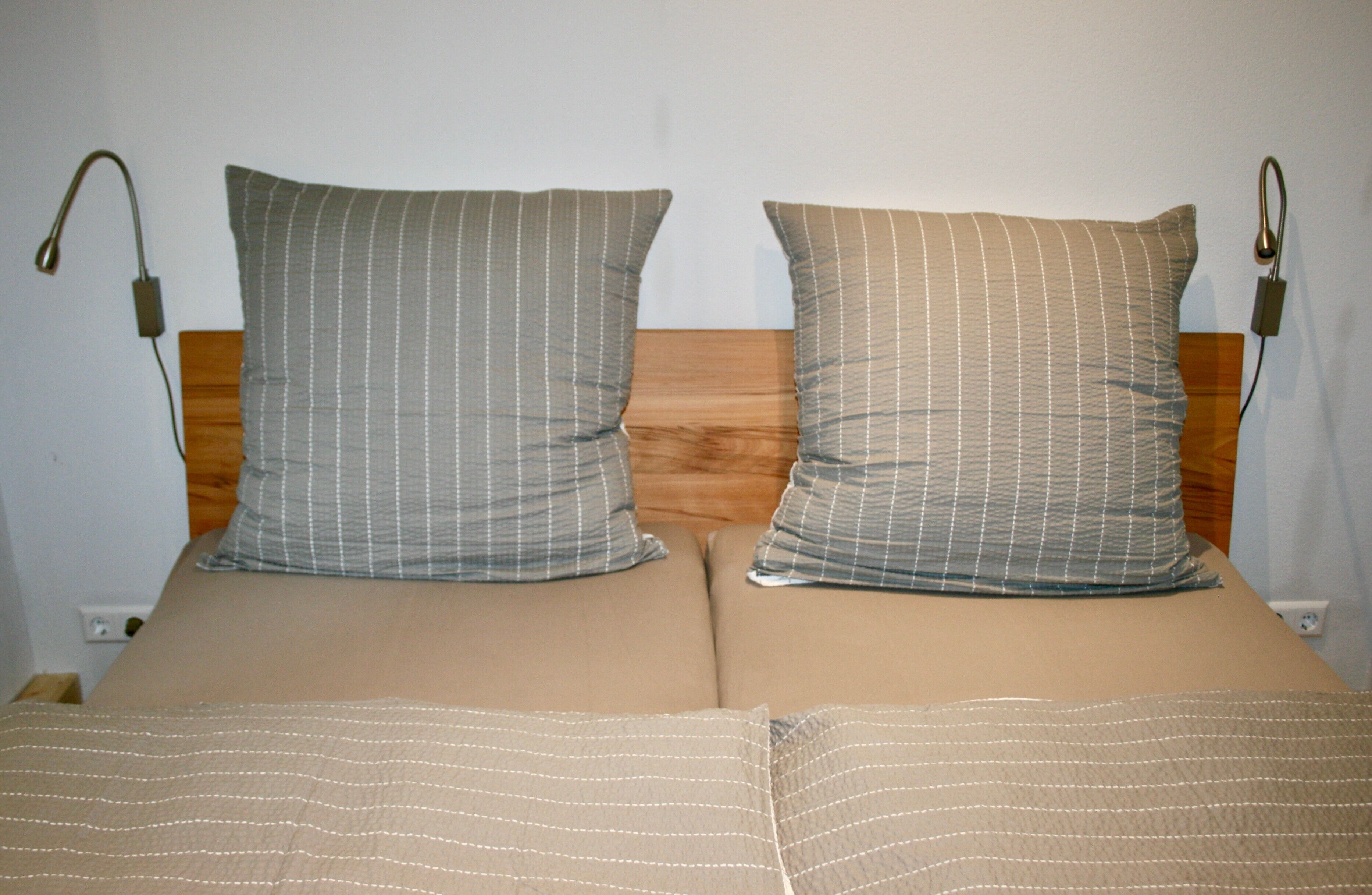 Un lit avec deux oreillers et une tête de lit en bois.