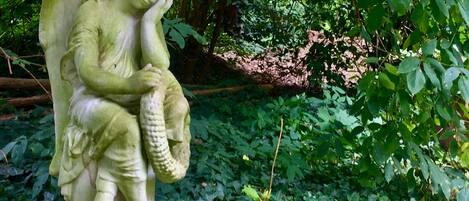 A statue of an angel holding a basket in a garden setting.