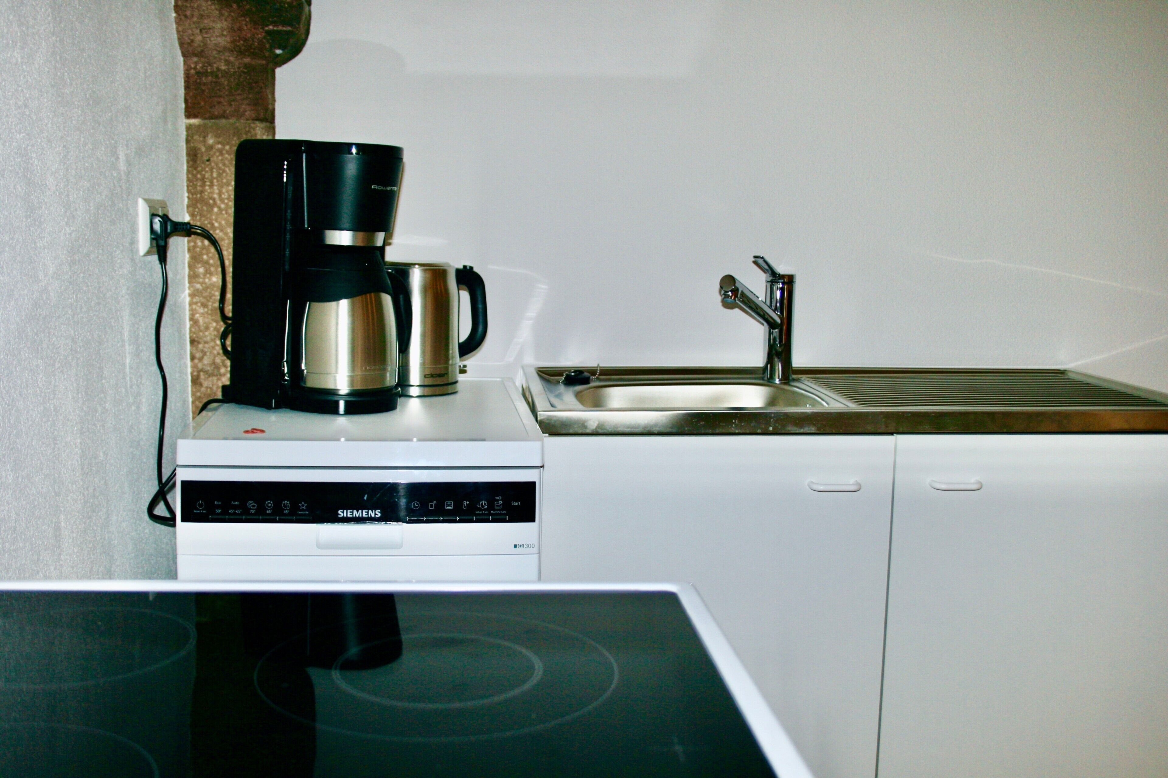 A kitchen with a coffee maker, a sink, and a dishwasher.