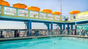Una piscina con un puente sobre ella, con sombrillas y una fuente.