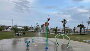 Un área de juegos con agua, con varias fuentes y columpios.