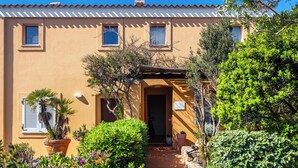 A building with a tiled roof, a central entrance, and potted plants around the entrance. - Valesmeralda Boutique Rooms  (Arzachena)