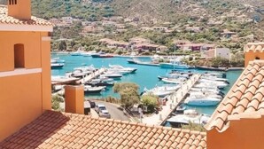 A coastal town with a marina, terracotta-roofed buildings, and mountainous terrain in the background. - Valesmeralda Boutique Rooms  (Arzachena)