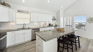 A modern kitchen with white cabinets, a granite countertop, and a central island with bar stools.