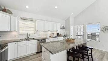 A modern kitchen with white cabinets, a granite countertop, and a central island with bar stools.