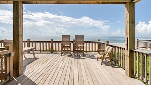 A wooden deck with two chairs facing the ocean.