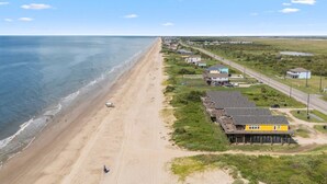 A coastal area with a sandy beach, a row of houses, and a road running parallel to the beach.