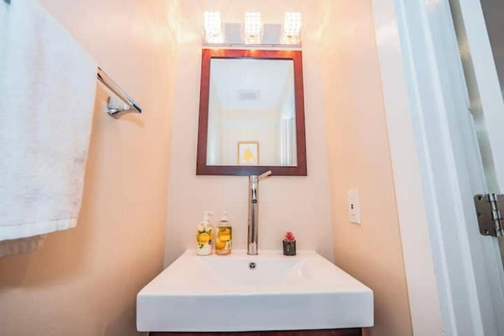 Un baño con un lavamanos blanco, un espejo y un perchero para toallas.