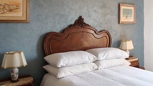 A bedroom with a wooden headboard, white bedding, and two bedside tables with lamps.