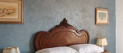 A bedroom with a wooden headboard, white bedding, and two bedside tables with lamps.