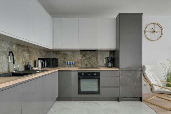 Una cucina moderna con mobili grigi, forno integrato e macchina per il caffè.