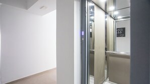 A modern elevator with a glass door, a control panel, and a sign indicating the floor number. - Ermou 44 City Hotel (Faliraki)