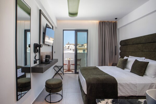 Une chambre d’hôtel avec un grand lit, un bureau avec une chaise, une petite table et un balcon avec vue.