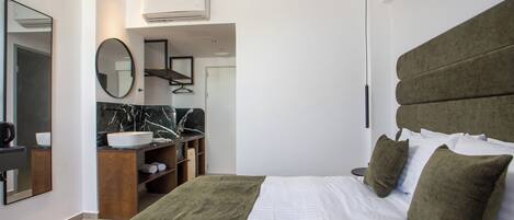 A modern hotel room with a large bed, a vanity with a marble countertop, a mirror, and a green headboard.