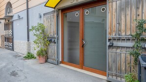 A building with a wooden door, a potted plant, and a metal gate. - Apartment 'Del Porto, Palermo' with Balcony, Wi-Fi and Air Conditioning (Palermo)