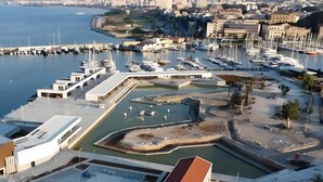 A marina with boats, a swimming pool, and a modern building with a sloped roof. - Apartment 'Del Porto, Palermo' with Balcony, Wi-Fi and Air Conditioning (Palermo)