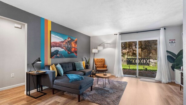 A modern living room with a sofa, armchair, and a painting on the wall.