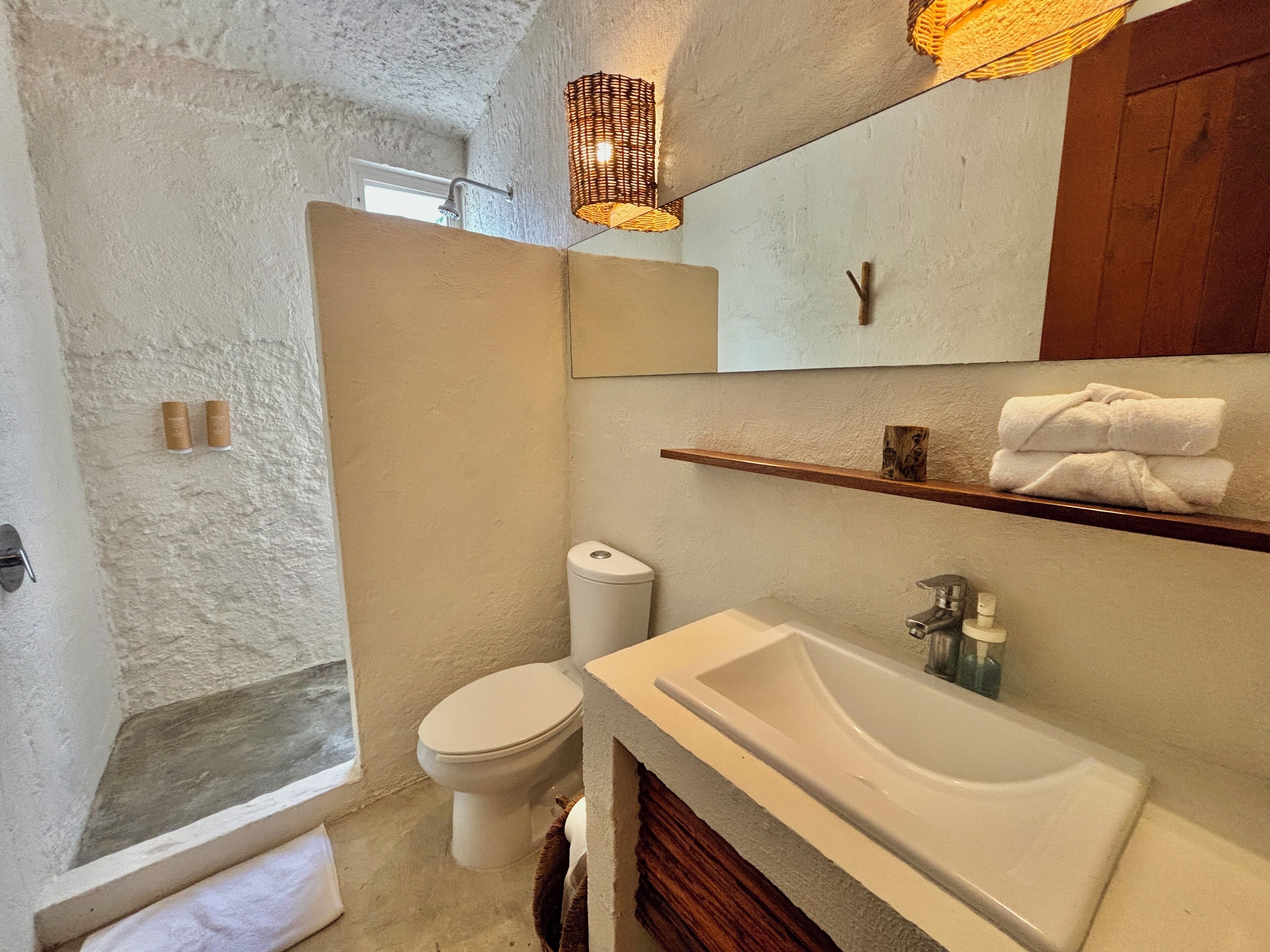 A bathroom with a white toilet, a sink, and a shower area.