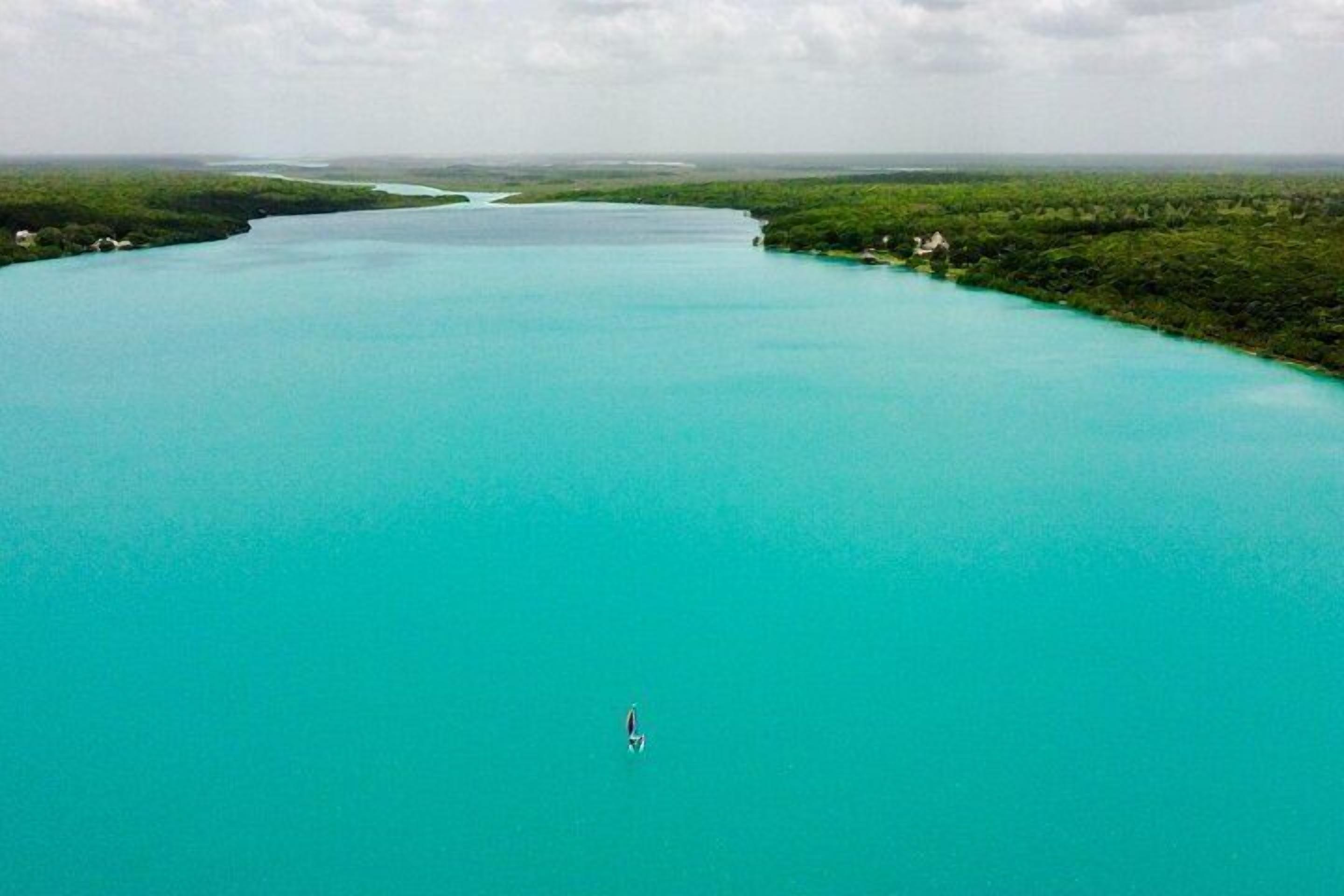 Une vue aérienne d’une vaste étendue d’eau turquoise, entourée d’une végétation luxuriante.