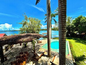 Un complexe hôtelier tropical doté d’une piscine, de chaises longues en bois et offrant une vue sur la mer.