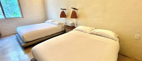 A room with two beds, a window, and a lamp.