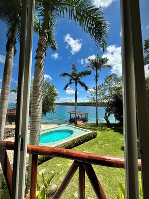 Une piscine entourée de palmiers, une terrasse en bois et une vue sur un lac et un quai.