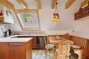 Eine Küche mit Holzbalken, einem Fenster, einer Spüle und einem Essbereich mit Holzmöbeln.