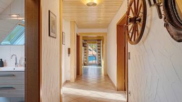 Un couloir avec un plafond en bois, une grande roue en bois et une vue sur un balcon.