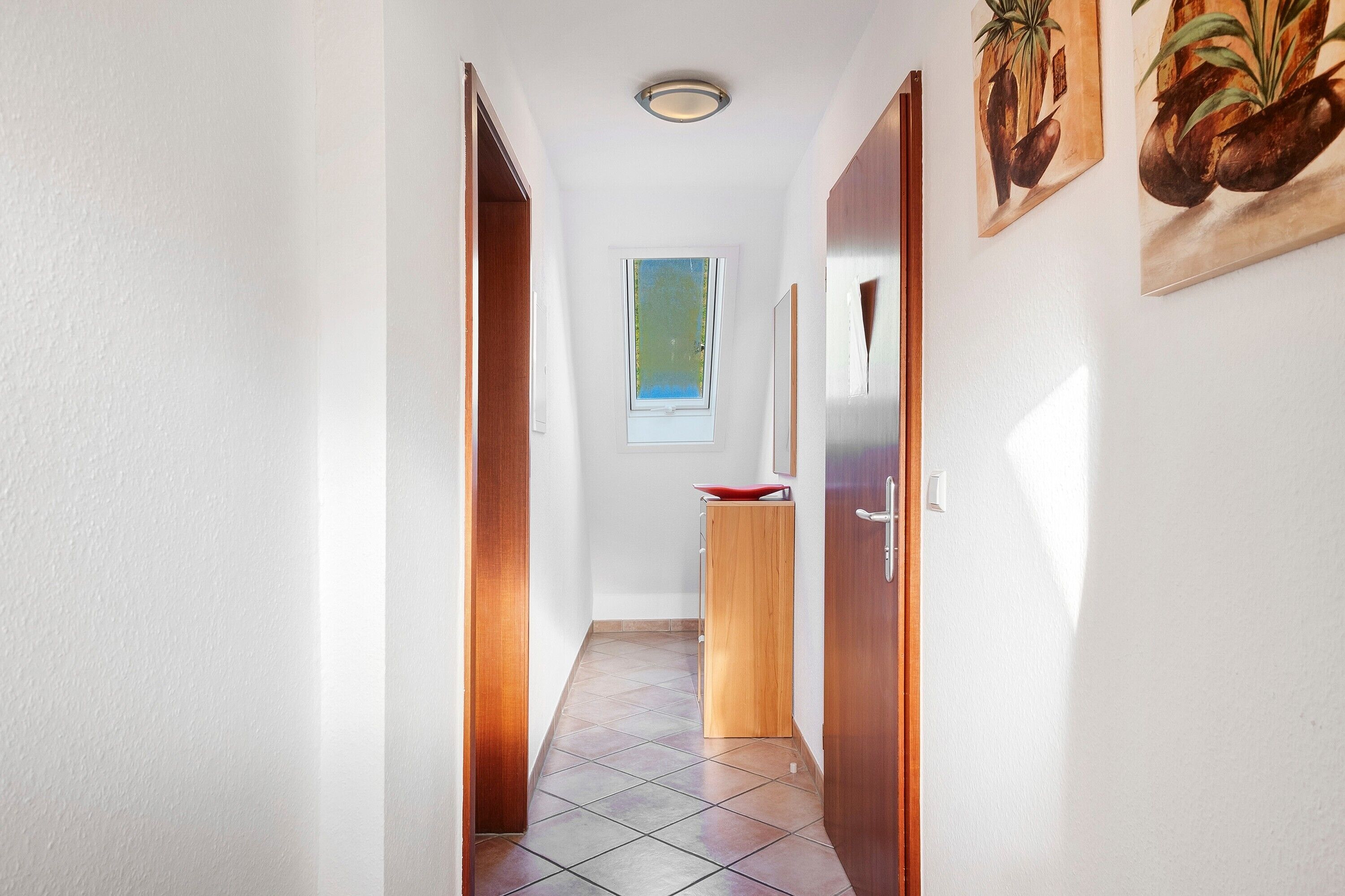 Un pasillo con una ventana, una puerta y un pequeño armario.