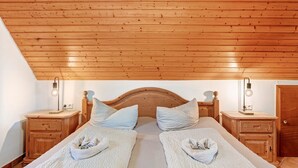 A bedroom with a wooden ceiling, two beds with towels, nightstands, and wall-mounted lamps. - Holiday Apartment 'Sonneneck' with Mountain View, Shared Pool and Wi-Fi (Wolfach)