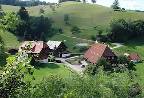 A rural village with traditional wooden houses, a clear road, and a hilly landscape.