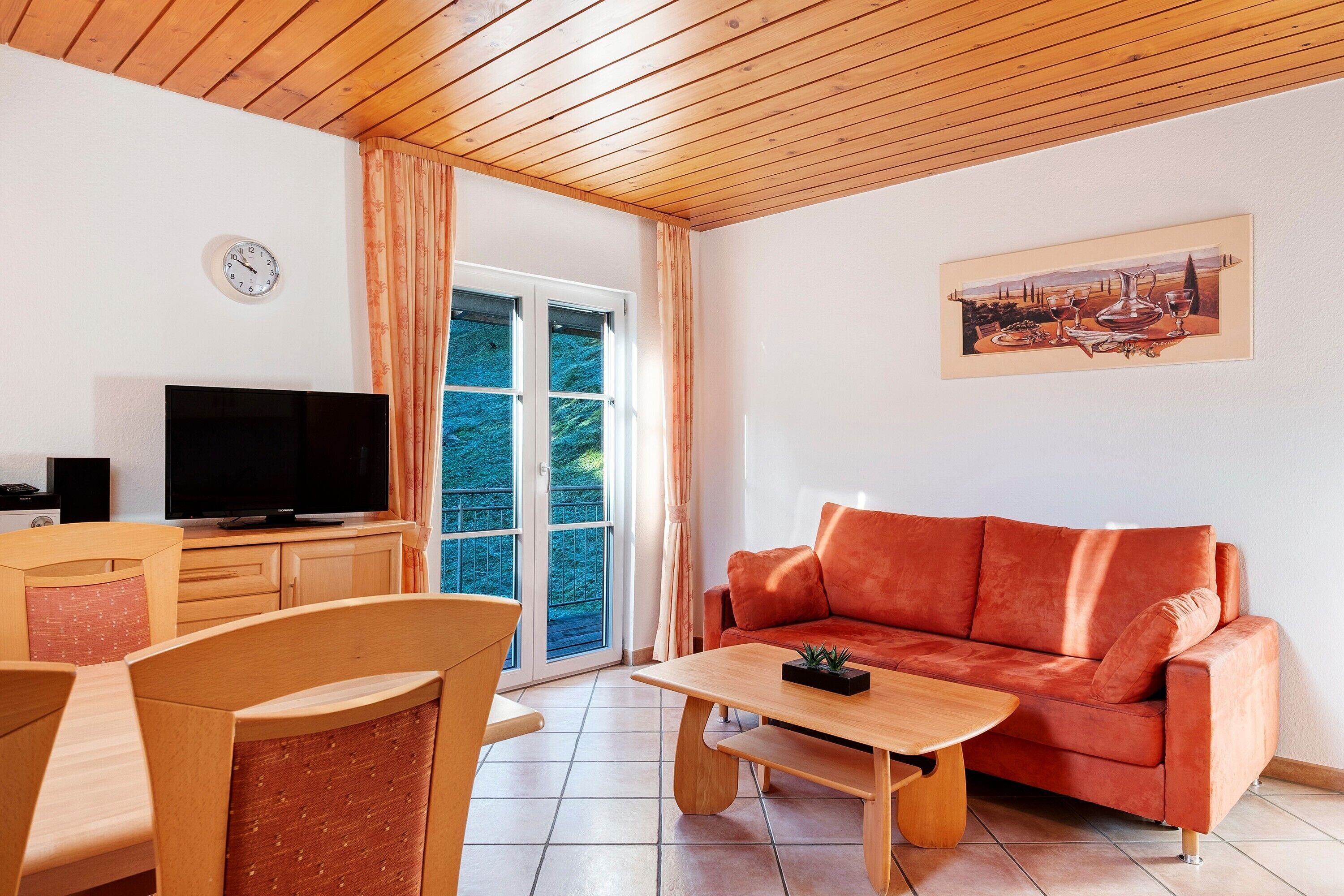 Een woonkamer met een bank, televisie, houten meubels en een schilderij aan de muur.
