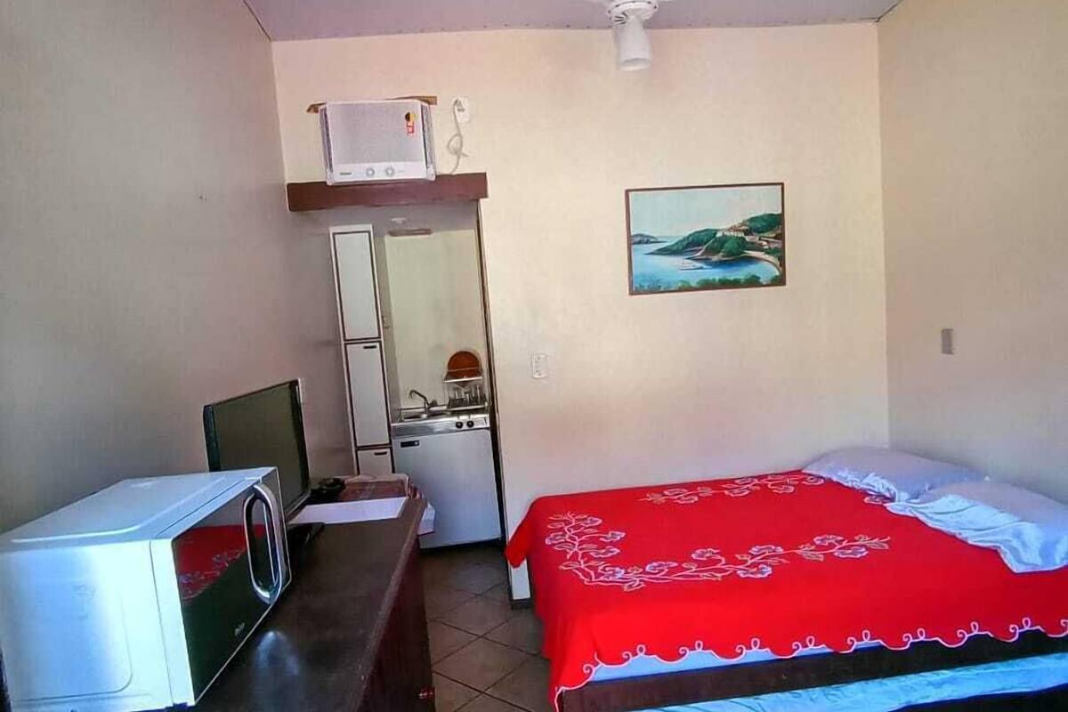 Une petite chambre propre, avec un lit, un bureau doté d’un micro-ondes, un ventilateur de plafond et un tableau accroché au mur.