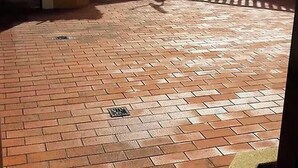 Une cour avec un sol en briques, des plantes en pot et une clôture en métal.