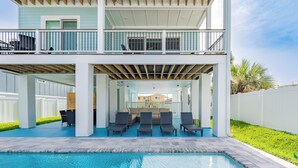 Ein zweistöckiges Haus mit Pool, Sitzgelegenheiten im Freien und einer überdachten Terrasse.