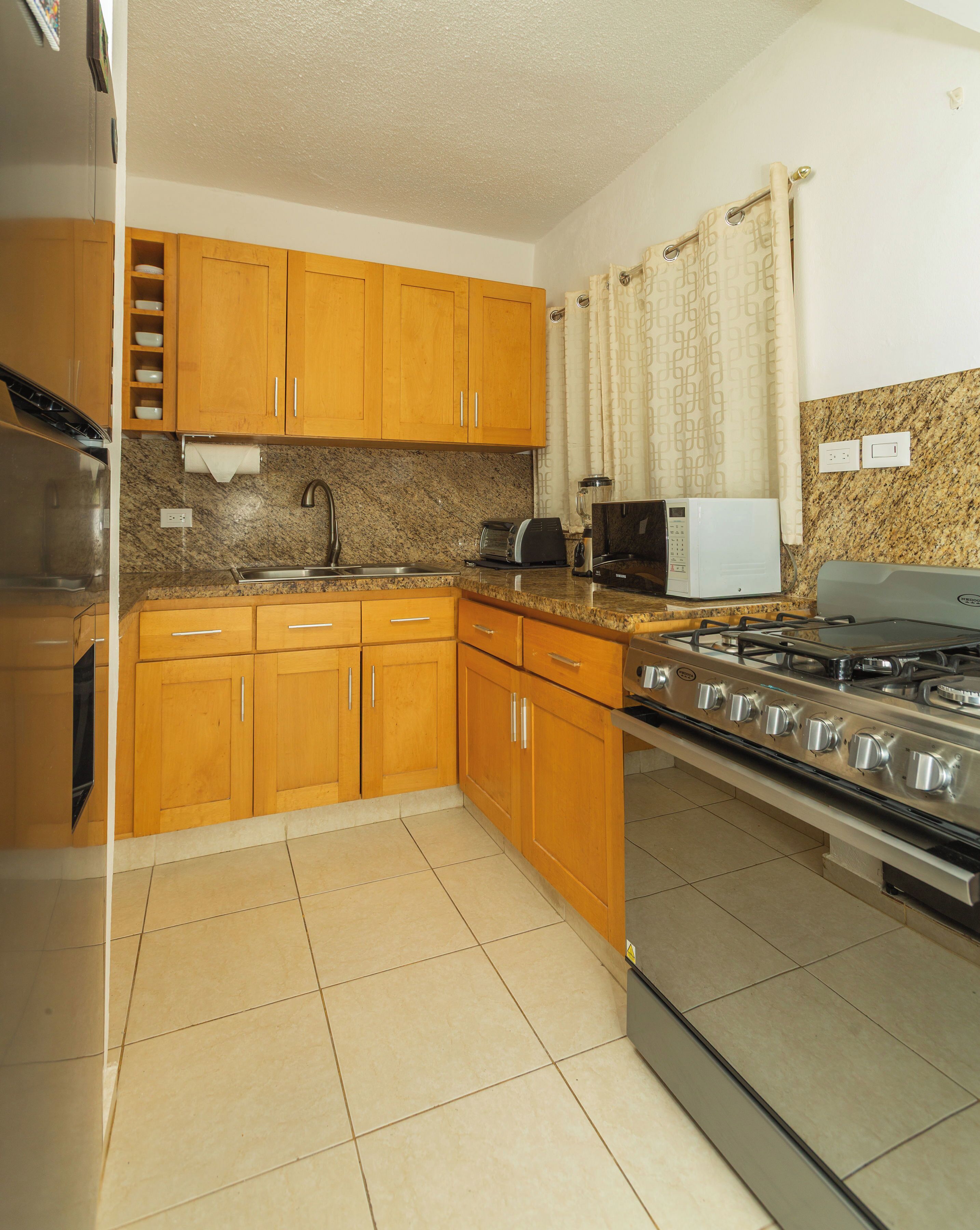 A kitchen with wooden cabinets, a stainless steel stove, a microwave, and a granite countertop.