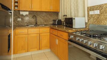 A kitchen with wooden cabinets, a stainless steel stove, a microwave, and a granite countertop.