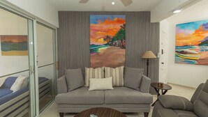 Ein modernes Wohnzimmer mit einem grauen Sofa, einem Couchtisch und einem Gemälde einer Strandansicht.