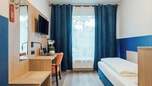 Habitación de hotel con escritorio de madera, una silla, una cama y un televisor fijado a la pared.