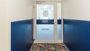 Un área de recepción con puerta de vidrio, una decoración en tonos azul y blanco, y un suelo con diseño.