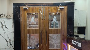 A reception area with a marble reception desk, wooden double doors with glass panels, and a striped carpet. - Kashi Vandanam (Varanasi)