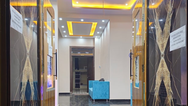 A hotel entrance with a marble wall design, a reception desk, and a staircase leading to the rooms. - Kashi Vandanam (Varanasi)